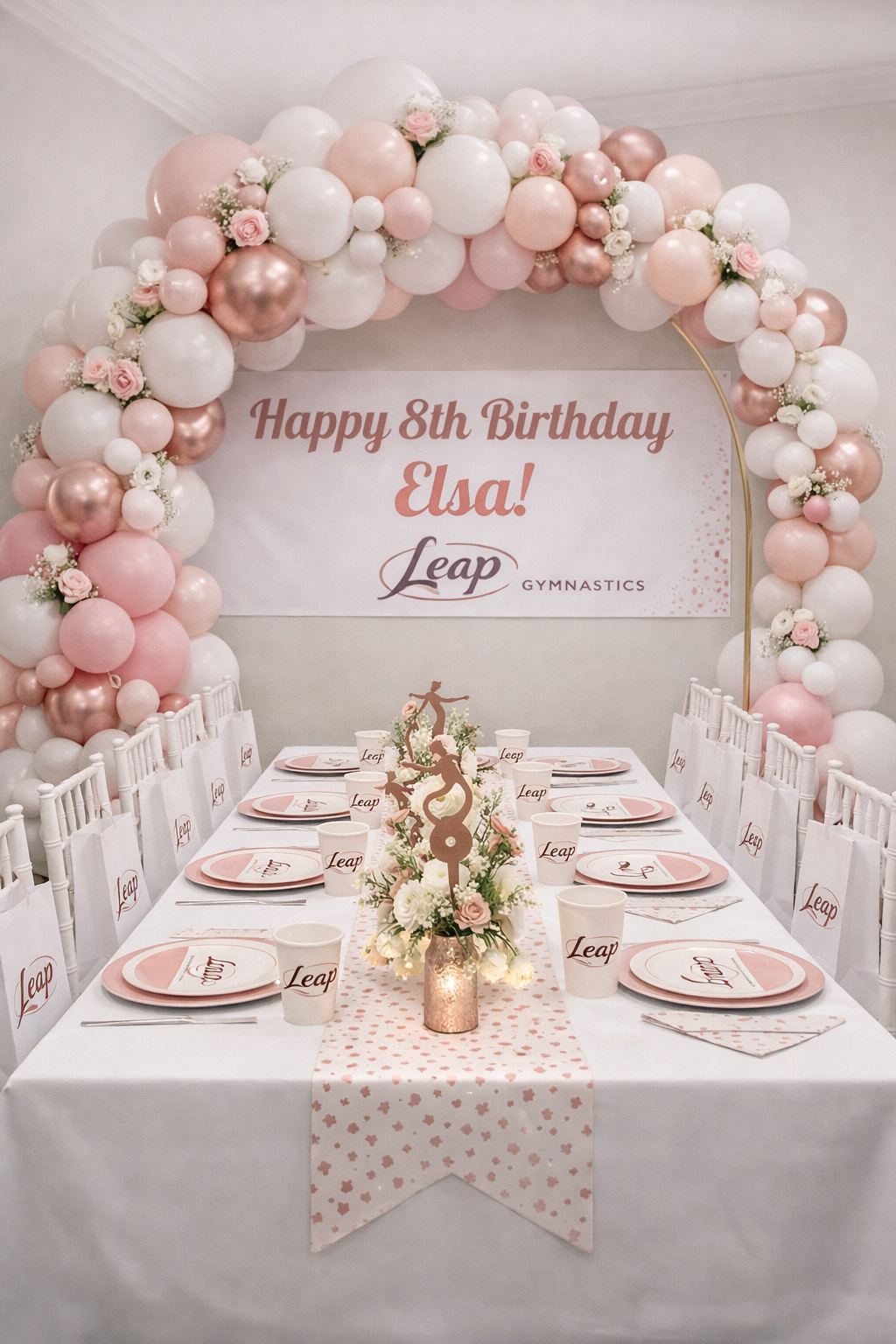 Leap Gymnastics Deluxe birthday party setup with gold and yellow balloon garland, personalized banner, branded plates, cups, and centrepiece